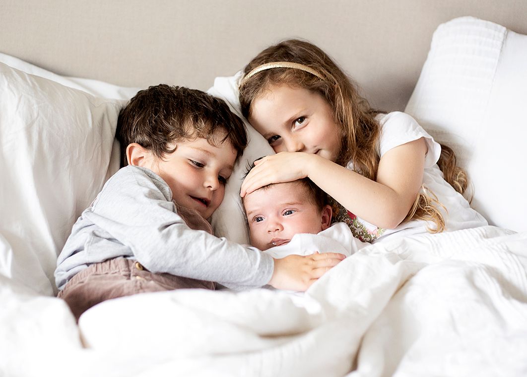 Newborn baby cradled by her two siblings in-home family session in Bridport, Dorset