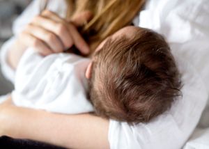 Closeup detail of newborn baby's fluffy hair in mother's arms