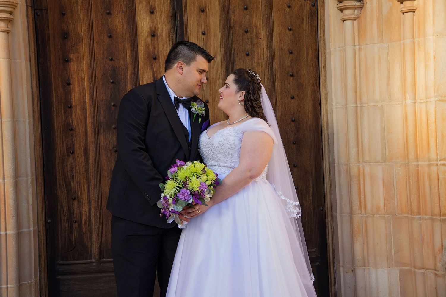 bride and groom posing infront of church doors