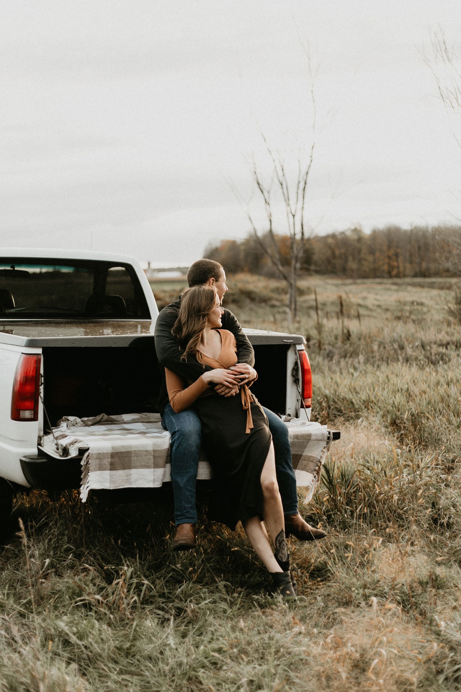 Engagement session in open field, couple sitting in truck