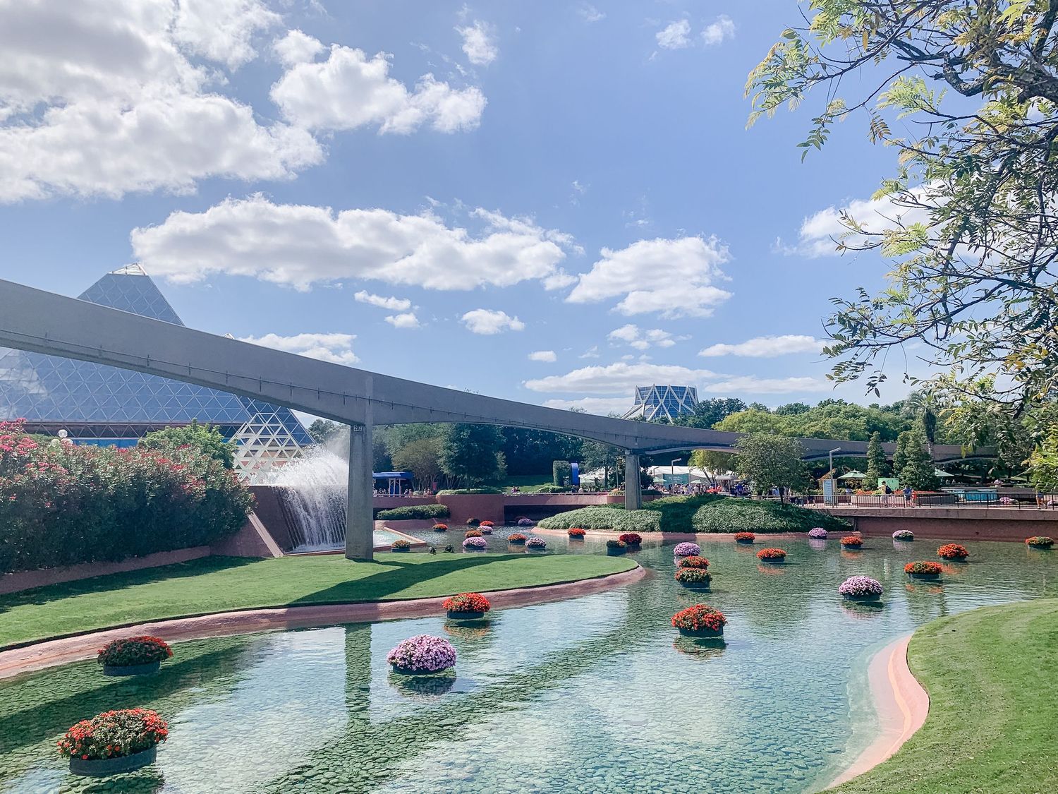 Colorful flower displays float on a winding water feature at an outdoor garden attraction.