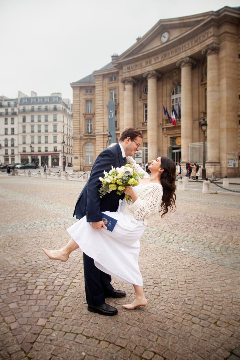 Romantic dip pose with bouquet in front of historic Parisian building.