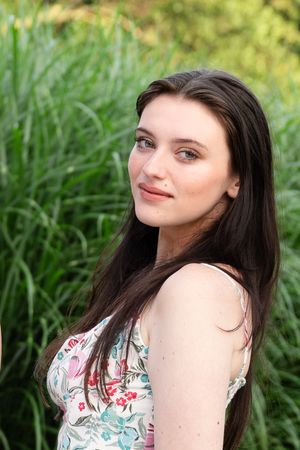 Portrait series in a garden setting with sunlit greenery and flowers in the background.
