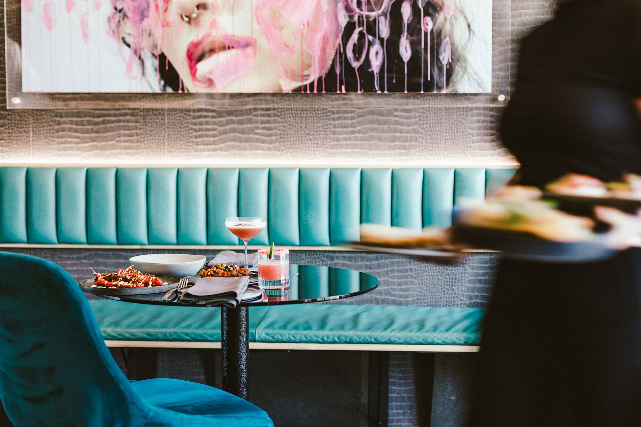Modern restaurant interior with turquoise booth seating and abstract wall art.