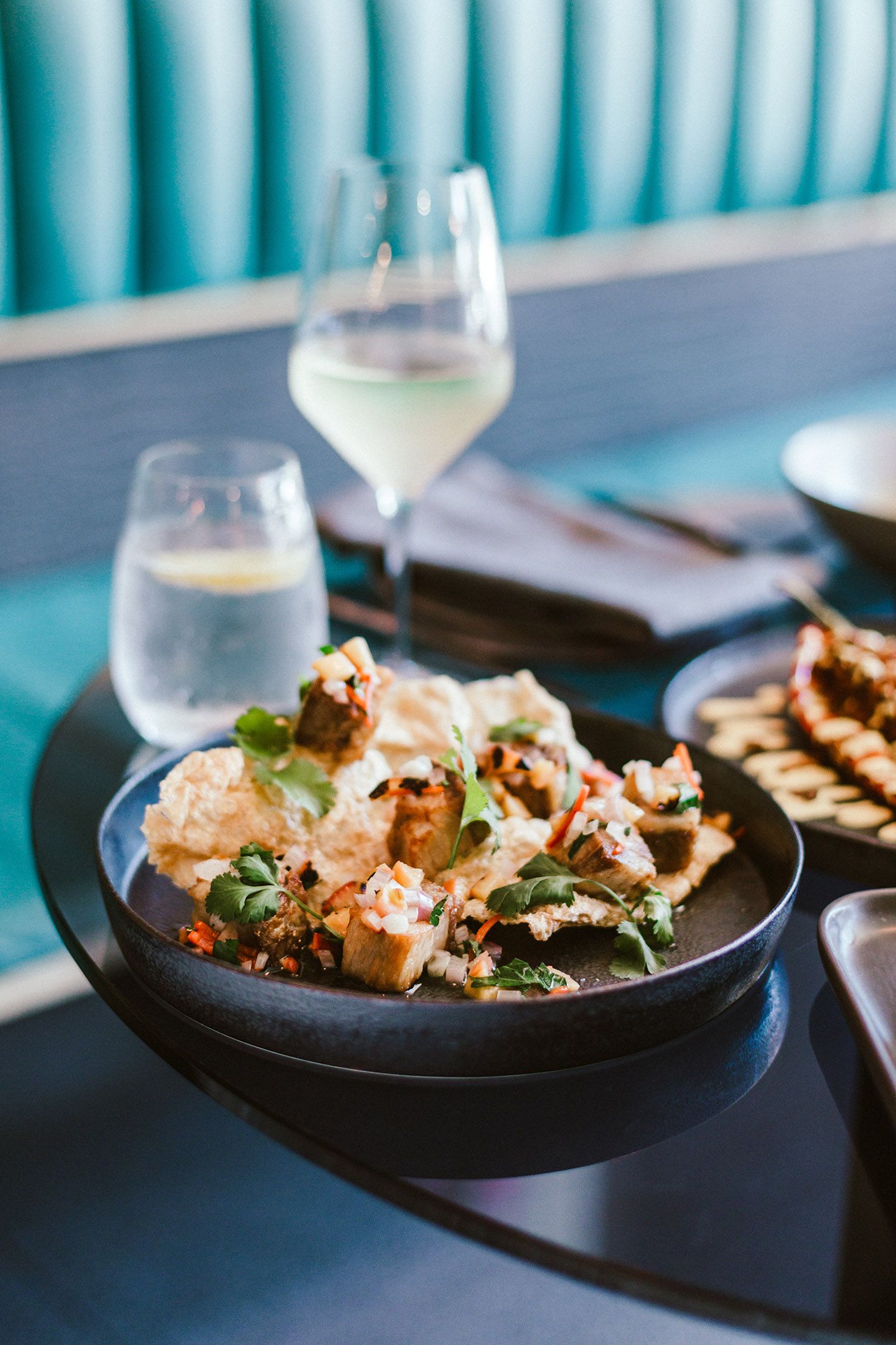Beautifully plated seafood dishes with garnishes on dark plates in upscale restaurant.