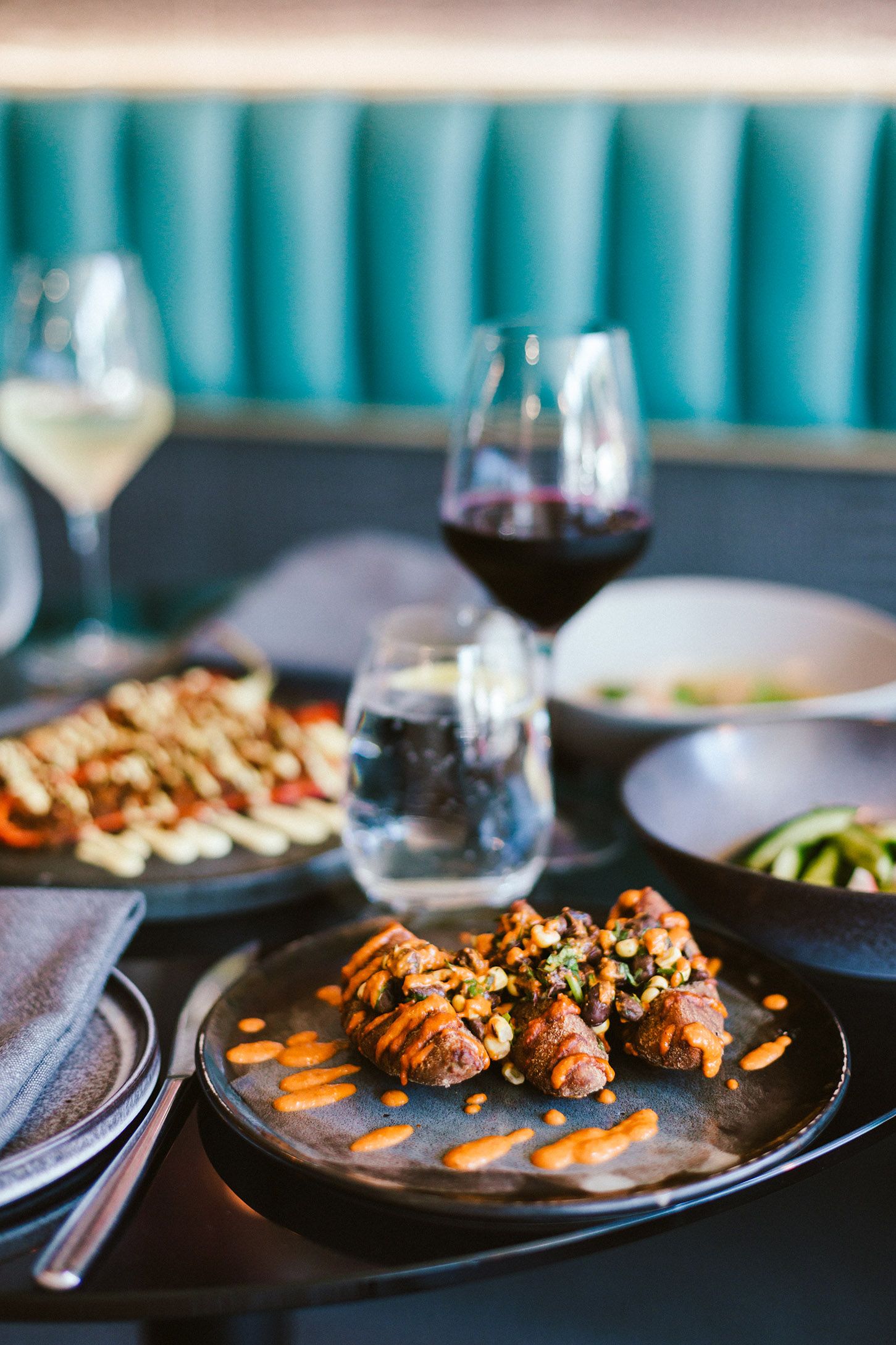 Grilled seafood appetizers garnished with nuts on black plates with wine pairings.