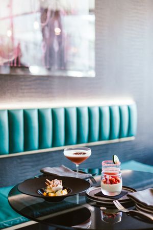 Elegant restaurant table settings with wine glasses and turquoise booth seating.