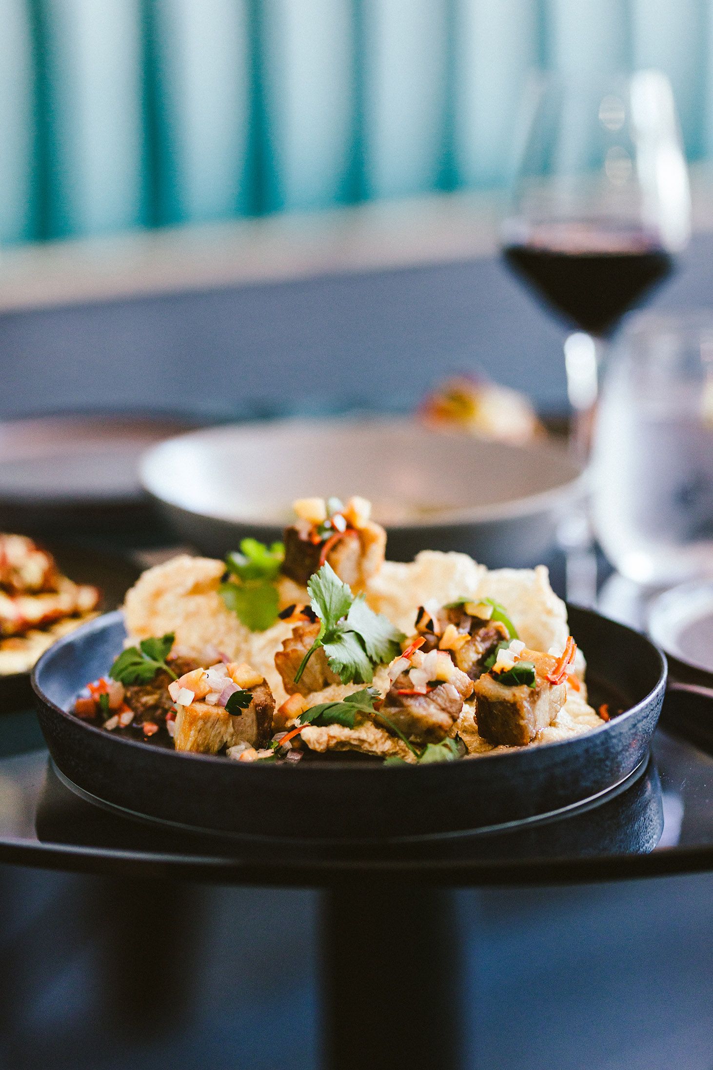 Gourmet seafood dish garnished with fresh herbs on black plate in restaurant setting.