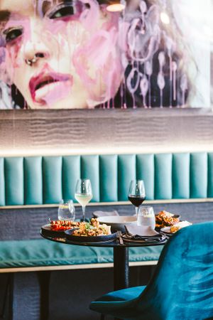 Modern restaurant dining area with turquoise booth seating and contemporary artwork displayed above.