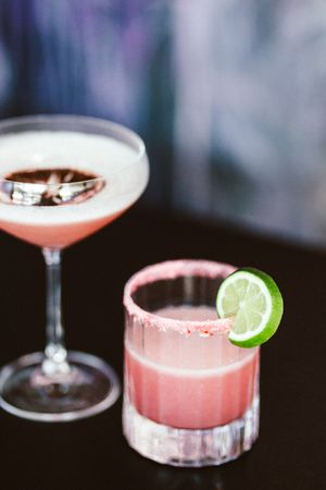 Artisanal pink cocktails with lime garnishes in elegant glassware.
