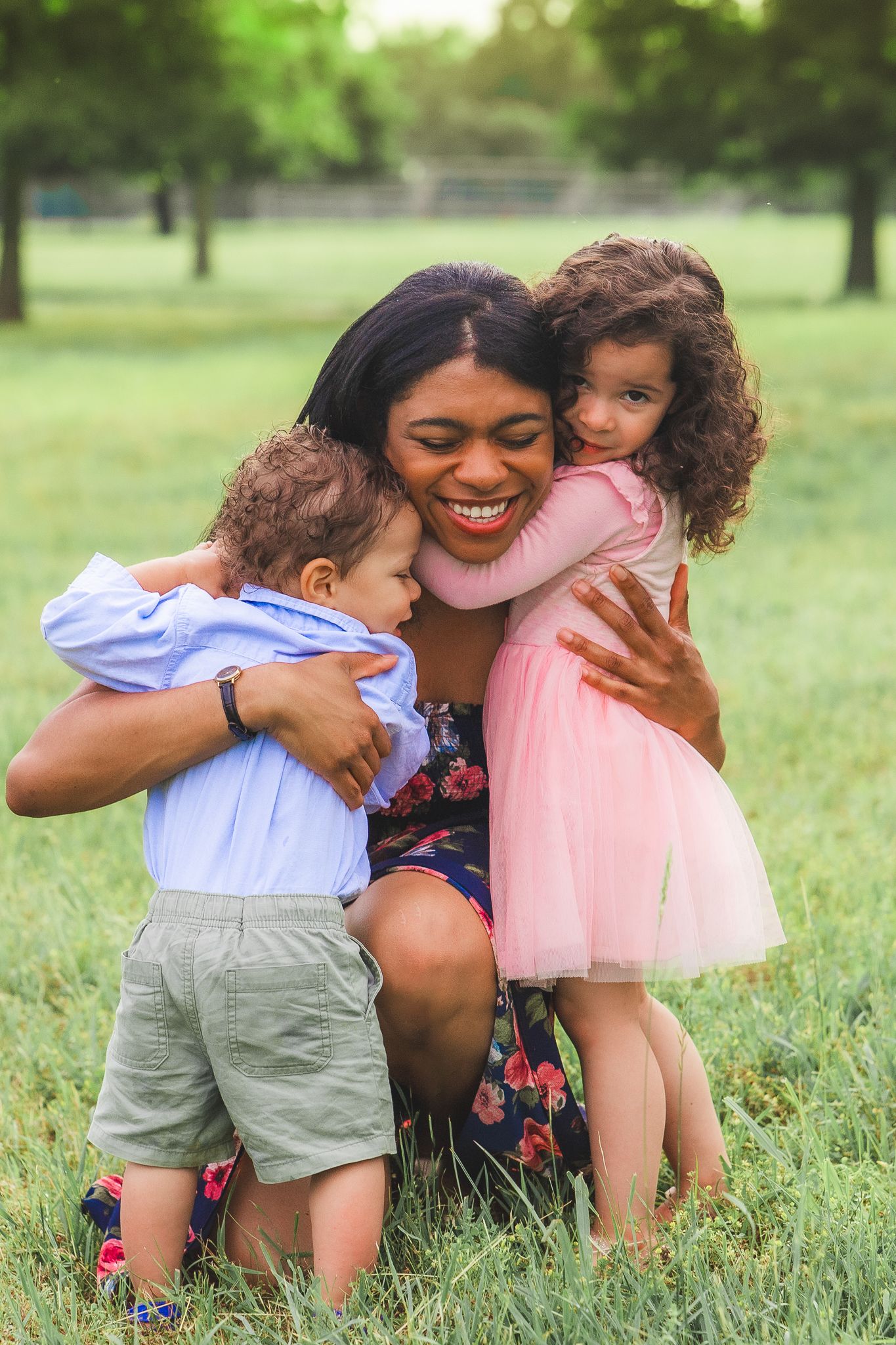 Family sharing warm embrace on grassy lawn during sunny day.