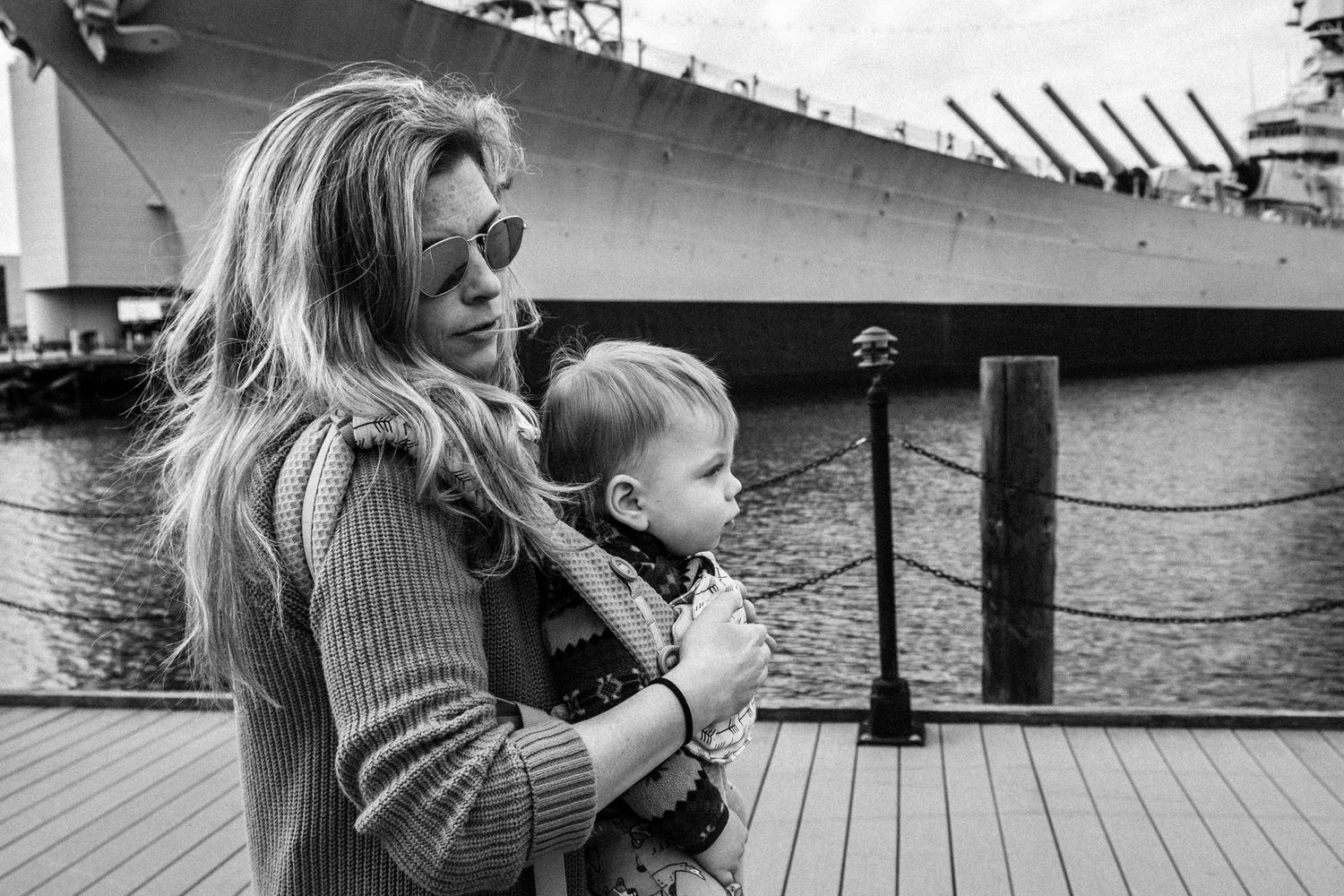 mom carrying a baby while walking beside a ship in norfolk, virginia