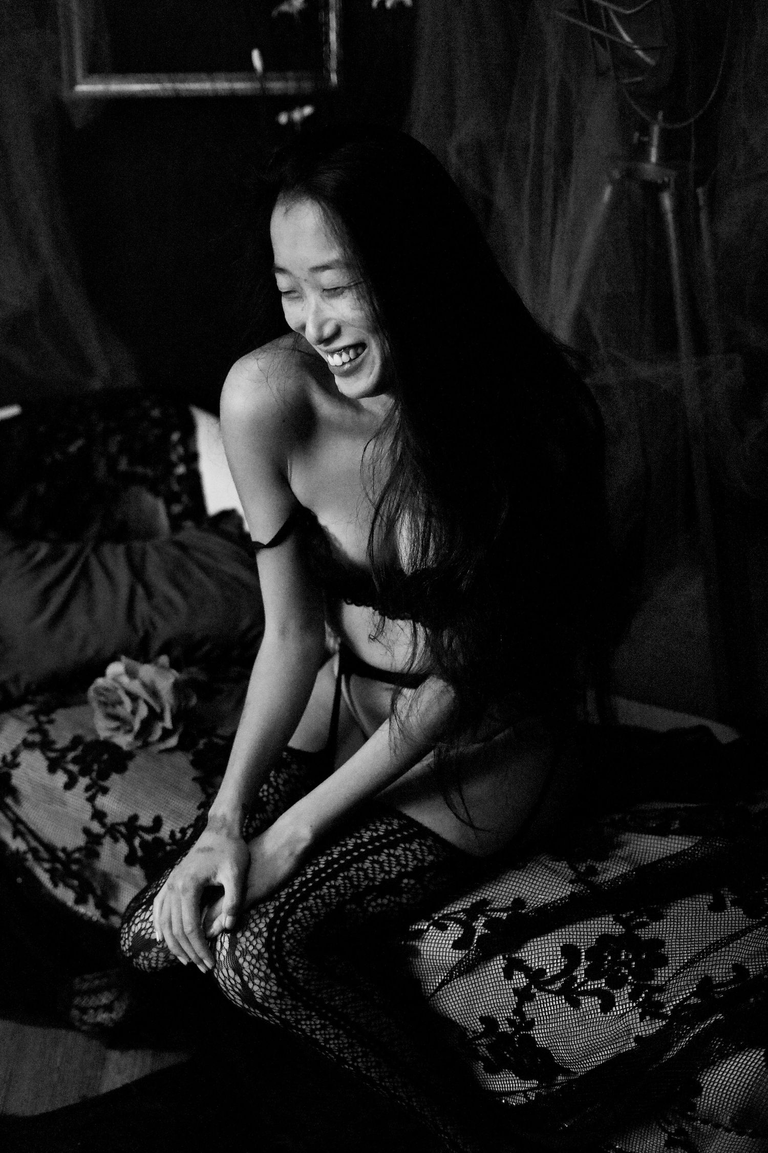 Black and white boudoir photo of person laughing joyfully during intimate photoshoot.