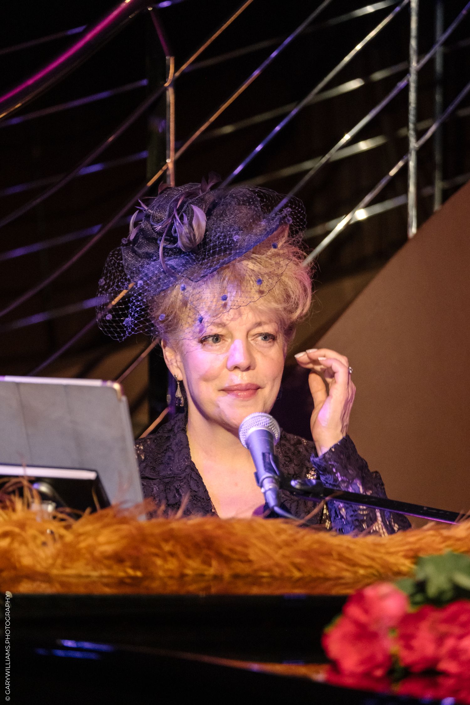 KT Sullivan at the piano in a purple fascinator at The Pheasantry In London.
