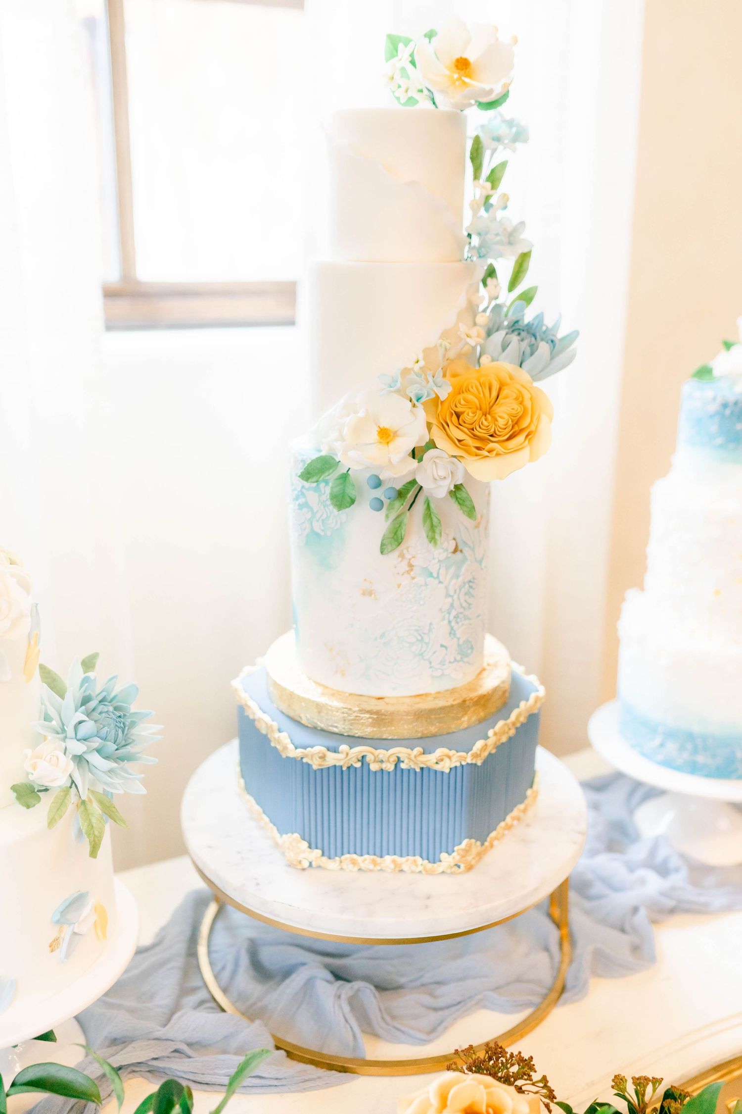 A three-tier wedding cake decorated with flowers and greenery.