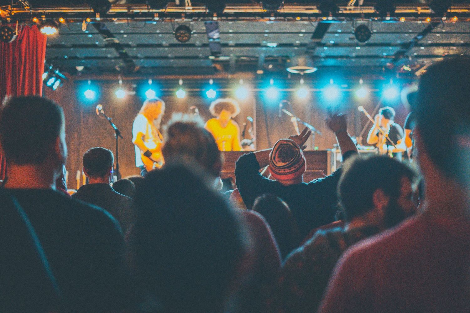 shot of stage during live show, audience is in focus, specifically a man waving his hands to music