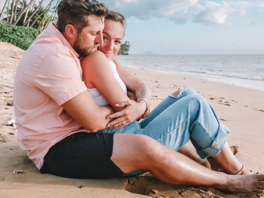 A couple relaxes on the sand during their romantic beach photoshoot.
