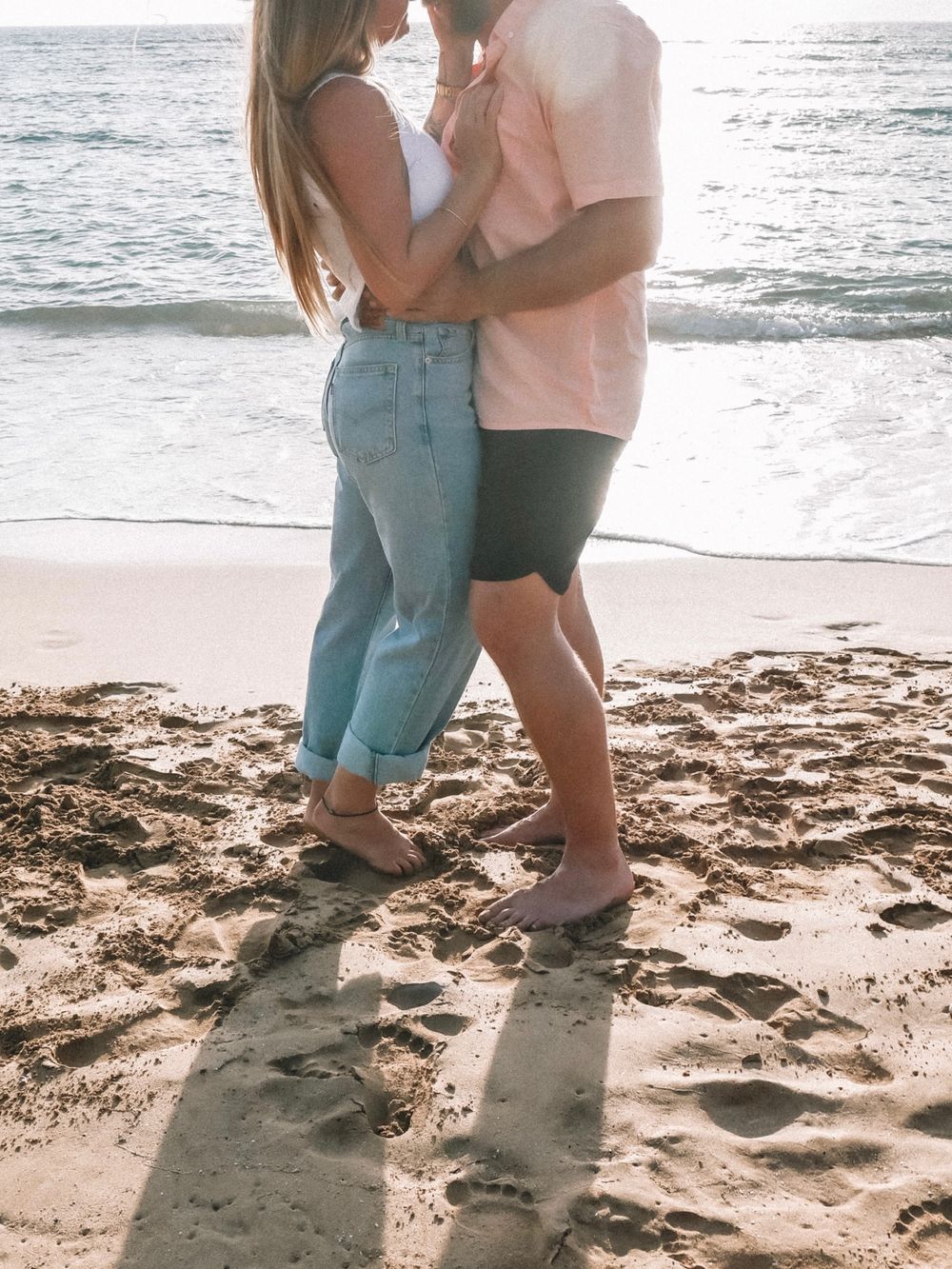 A couple's feet leave footprints in the sand as they share intimate moments on the beach.