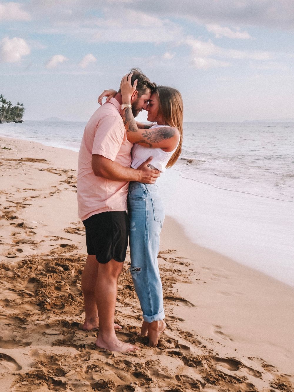 A romantic couple shares intimate moments on a sandy beach during golden hour.