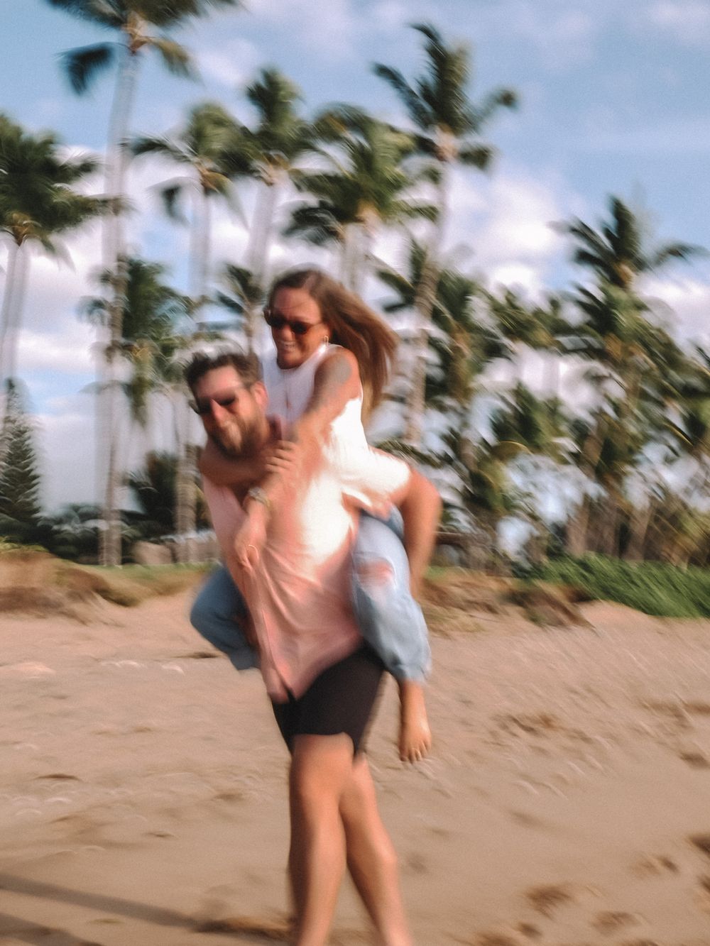 Joyful dance lift moment on a tropical beach with palm trees in background.