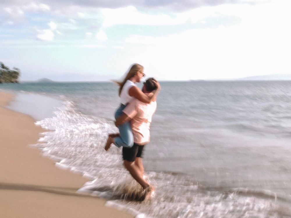 Playful moment captured on a tropical beach with waves crashing nearby.