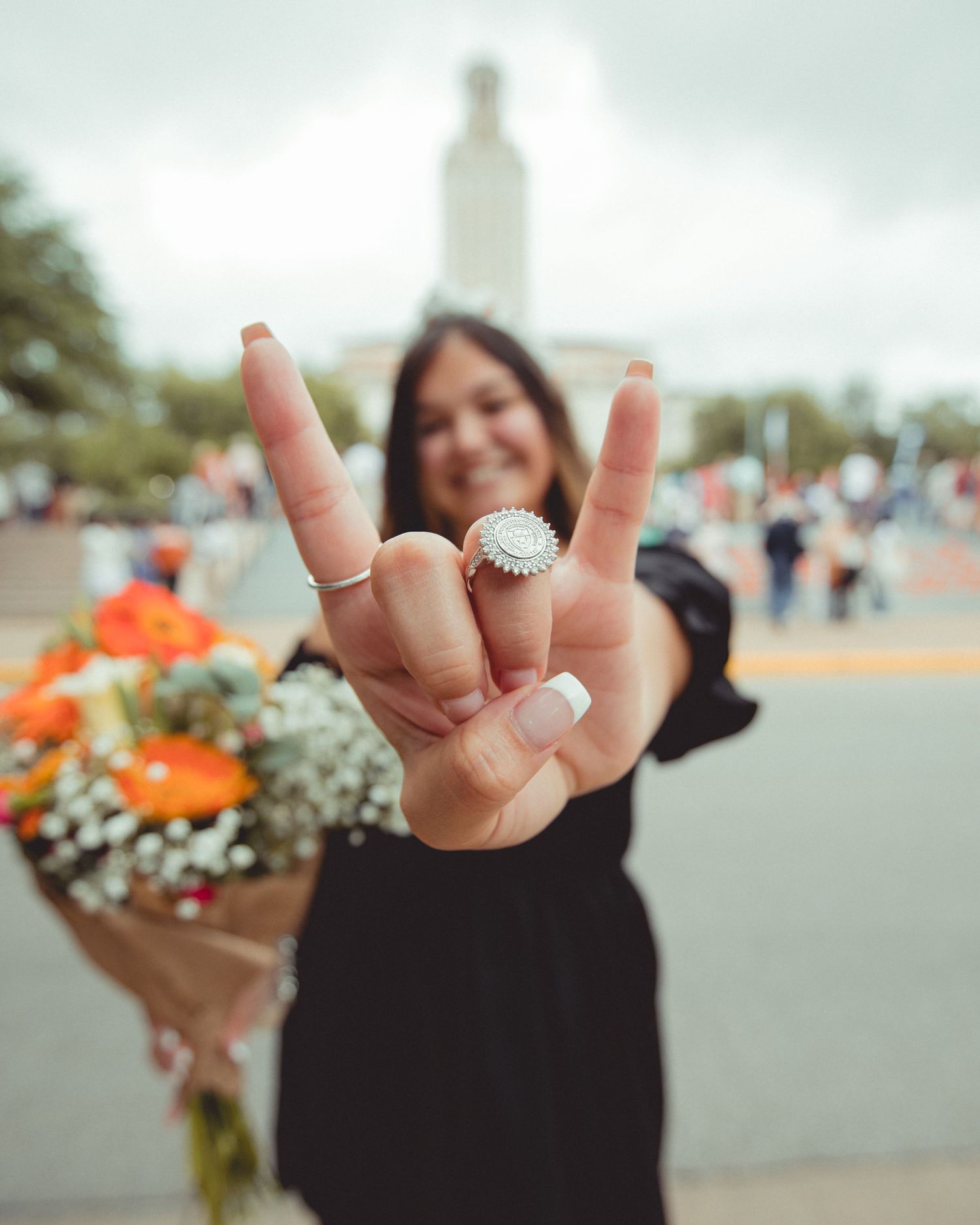 Close-up of hands making rock and roll gestures while holding colorful flowers.