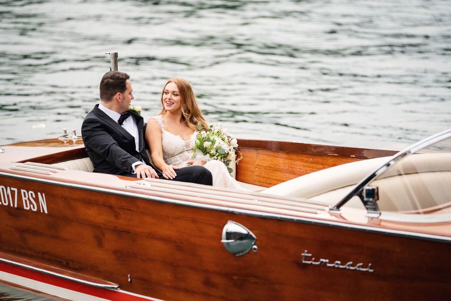 Classic wooden boat with newlyweds cruising across calm waters.
