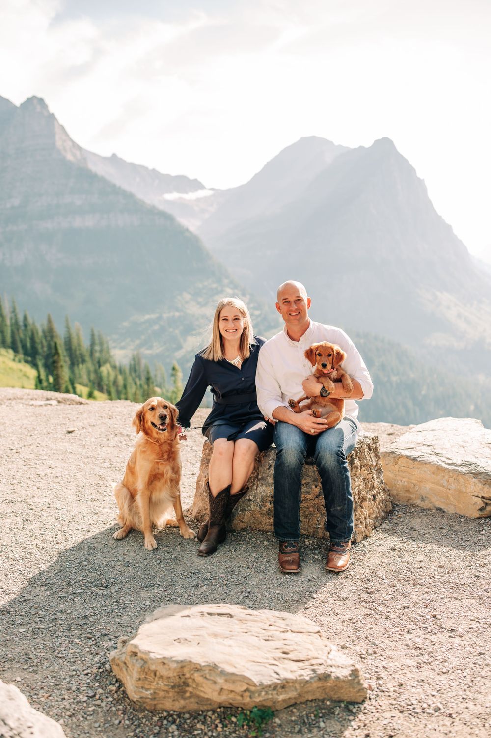 couple sitting on a rock with their two dogs with them