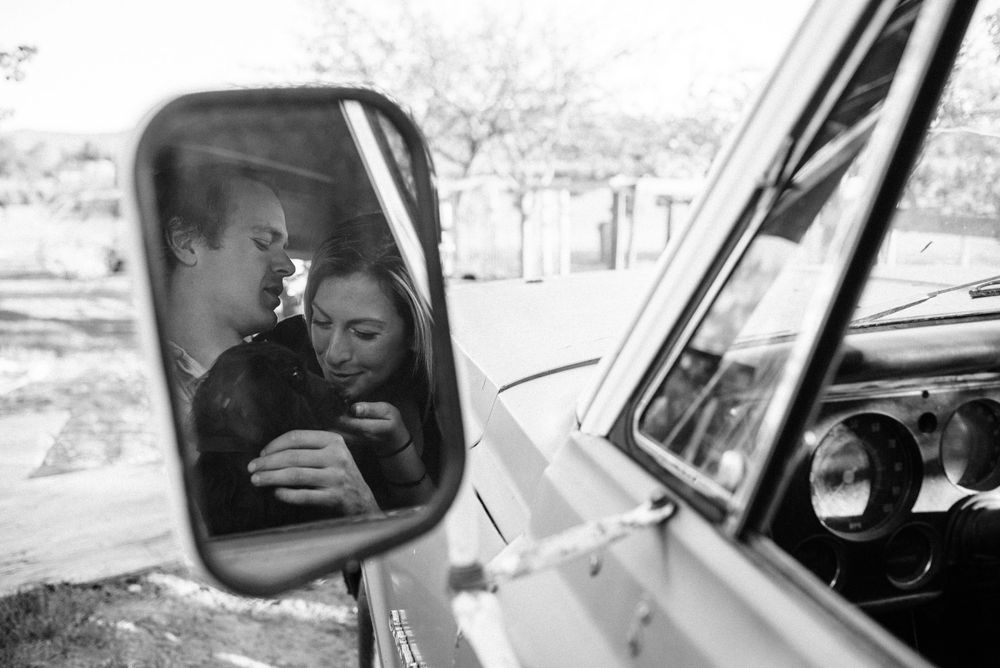 side mirror of a car, reflection of a couple and their dog