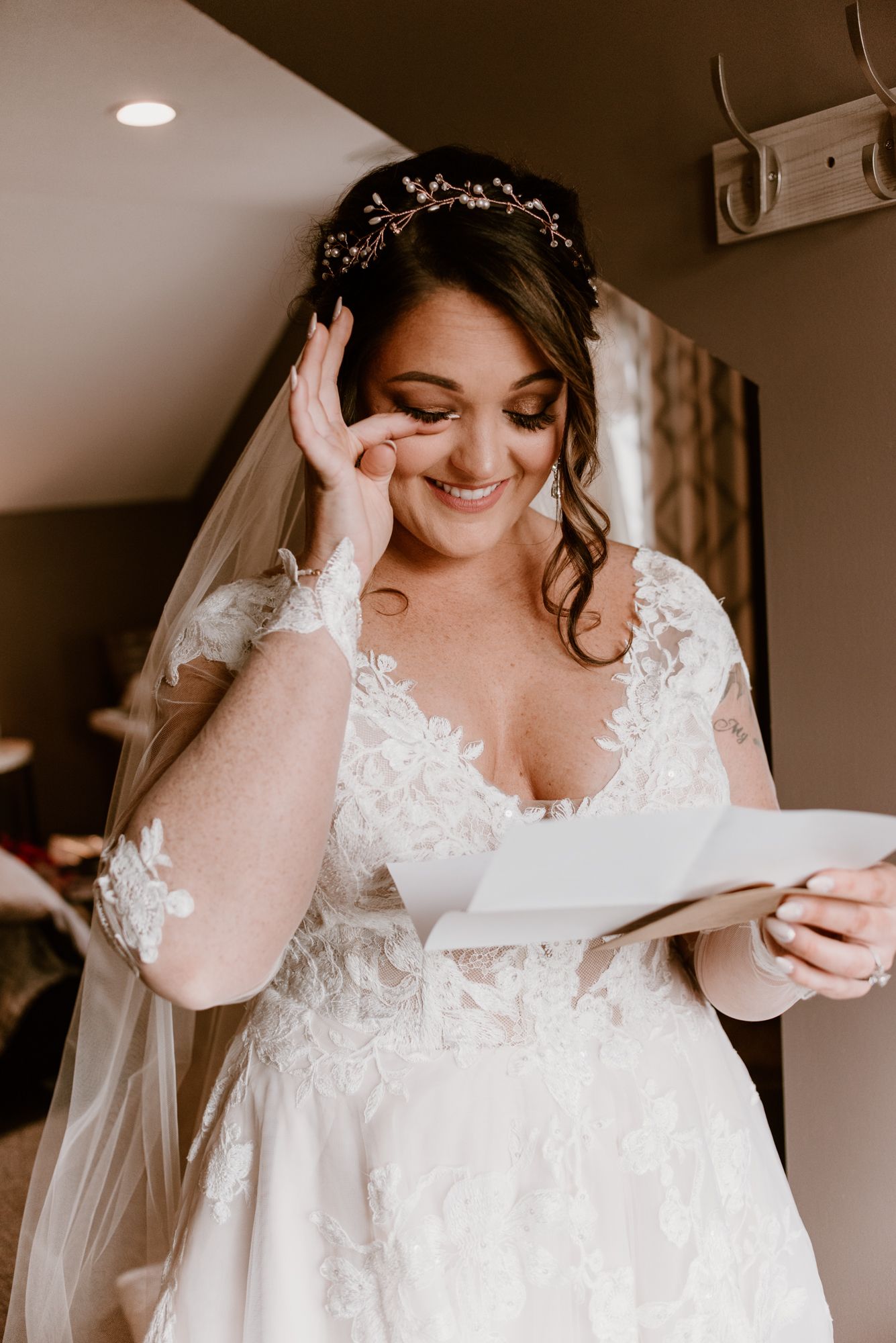 Bride reading letter while getting ready in elegant lace wedding dress.