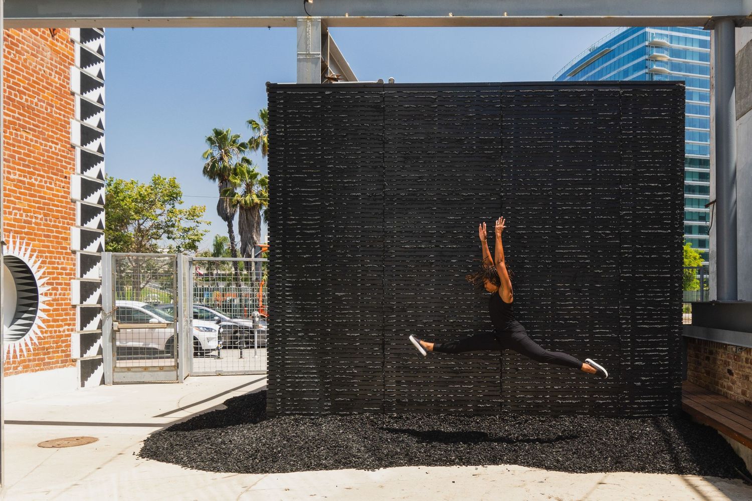 Artistic black water wall installation with cascading water against an urban backdrop.