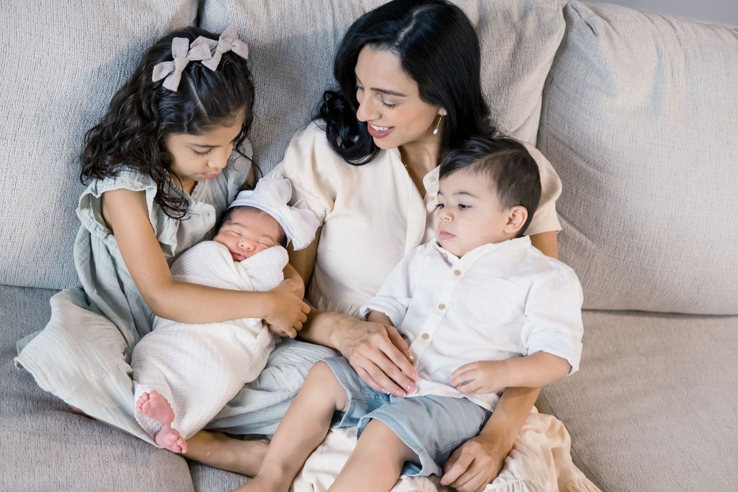 sister is holding newborn baby girl with mom and brother at home in Syracuse Utah Davis County.