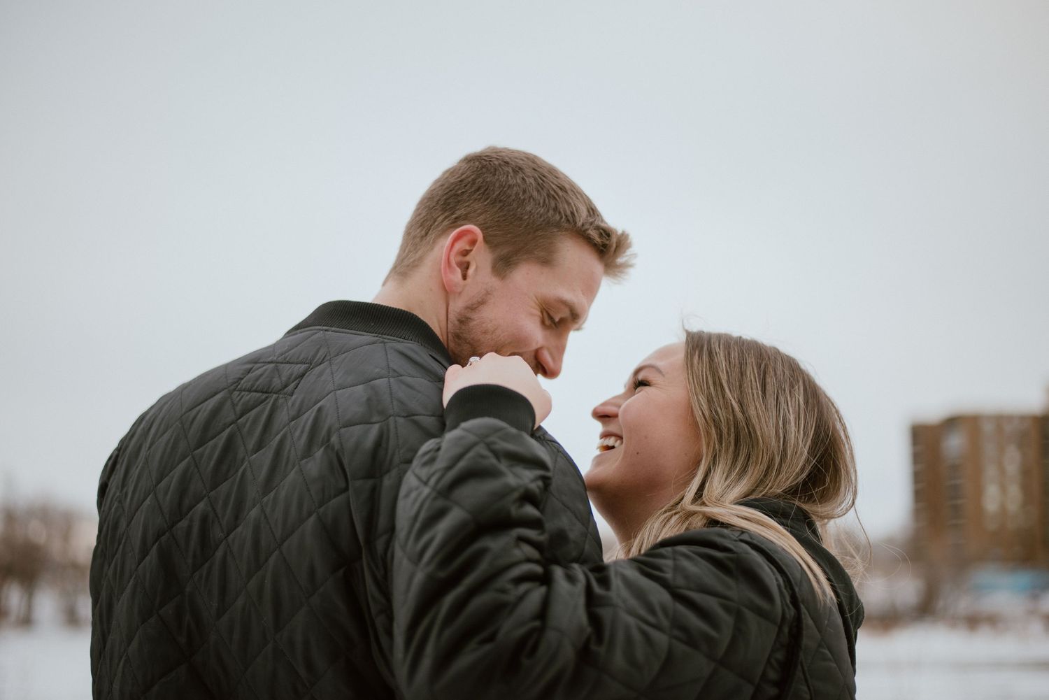 A tender winter moment between two people in dark coats.