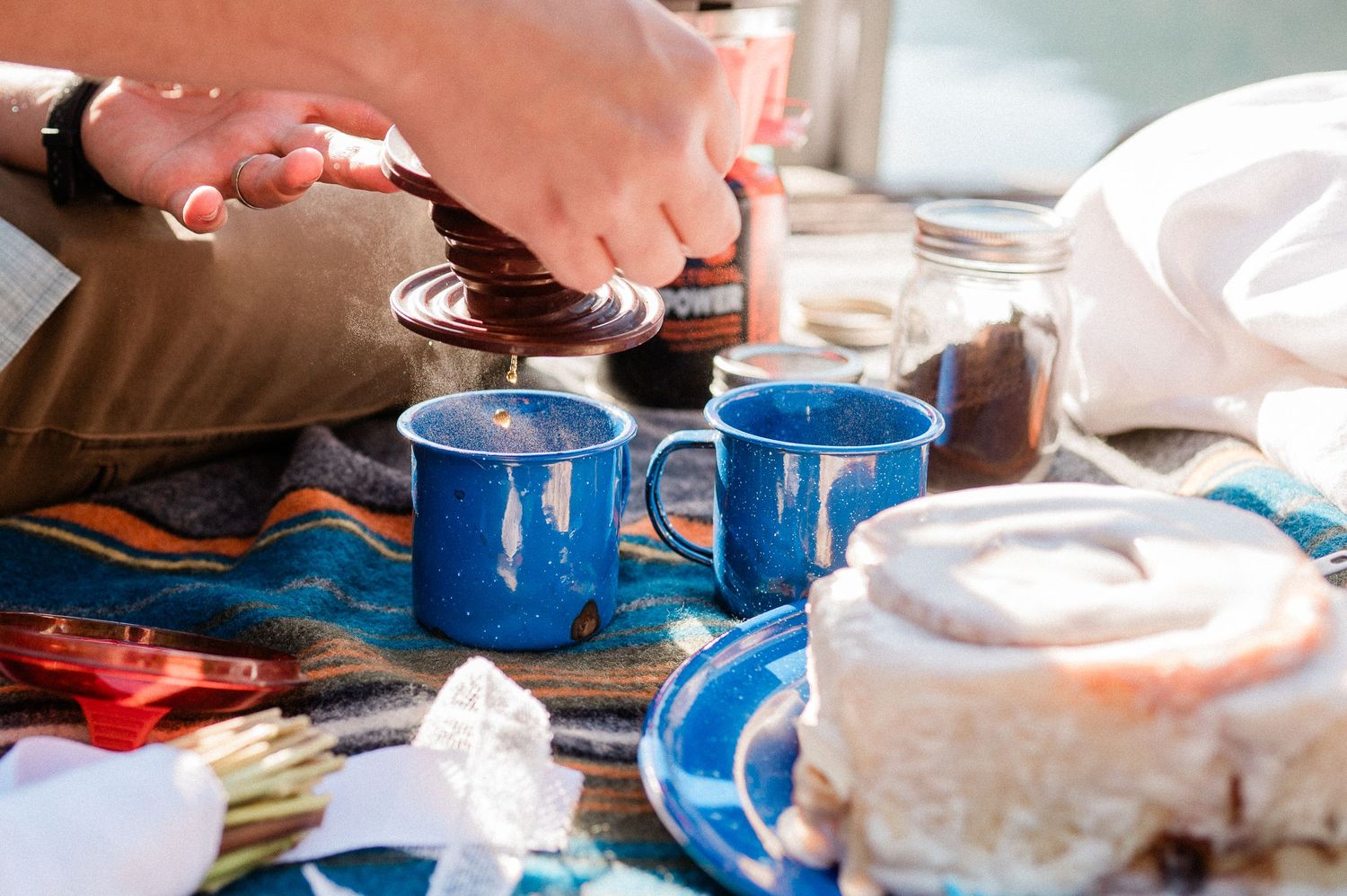 couple making coffee together into blue steel camping mugs