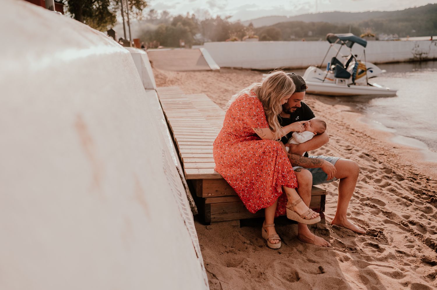 A couple sharing an intimate moment on a beach bench at sunset.