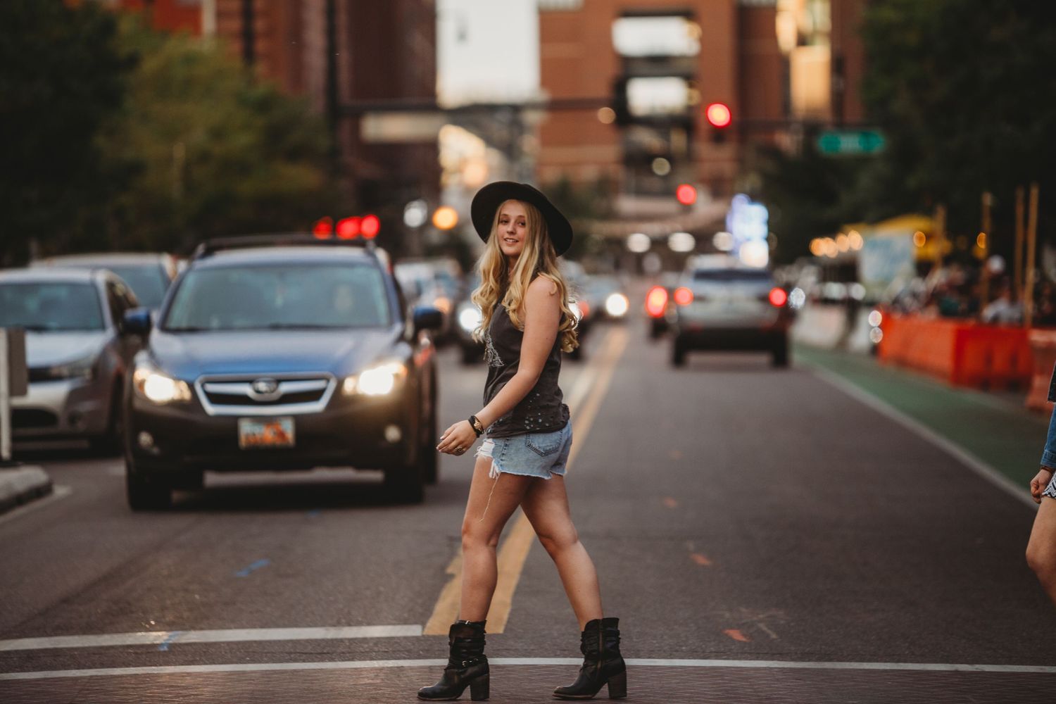 Street style photo on urban road with city traffic and buildings in background.