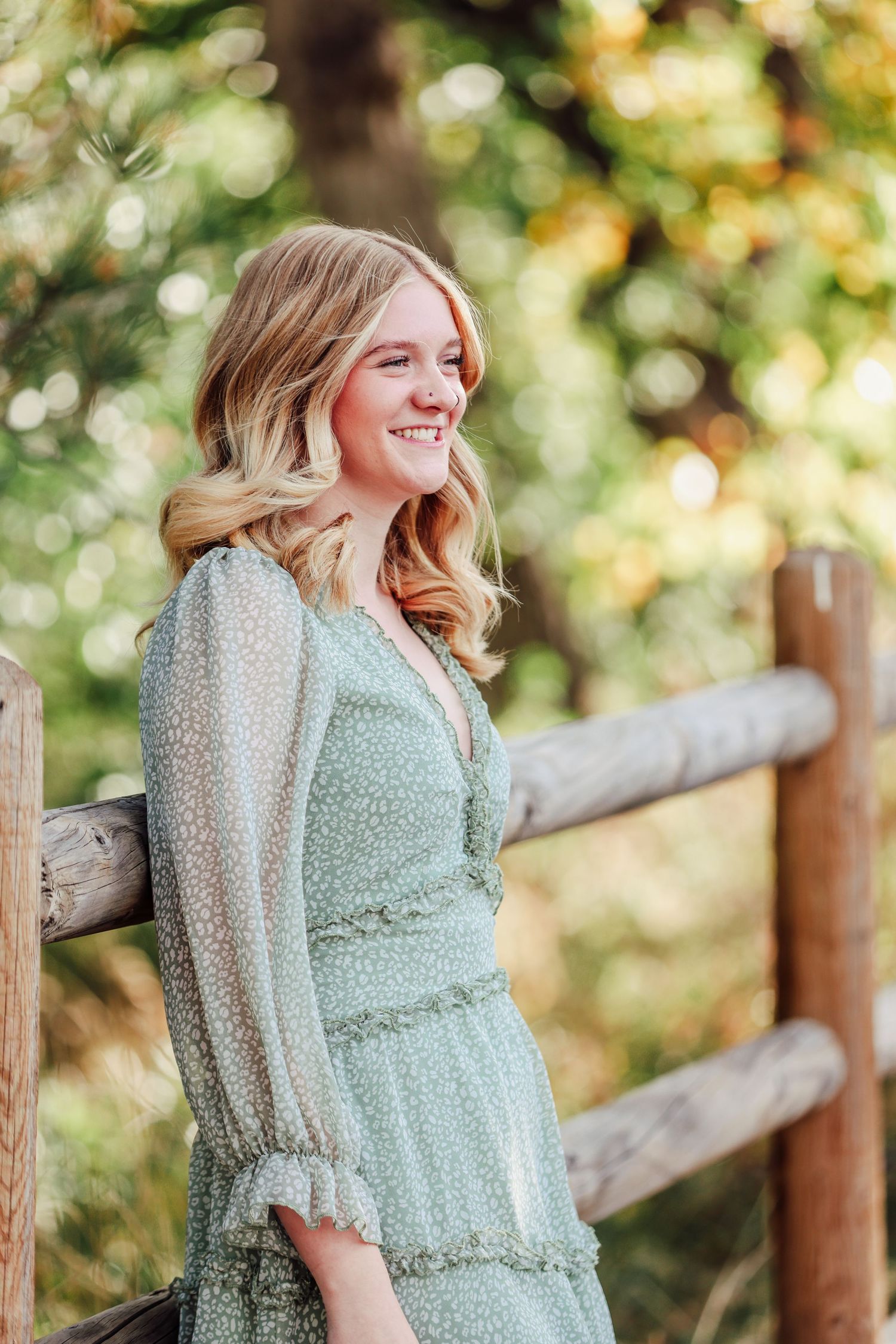Portrait by wooden fence wearing mint green dress with soft natural lighting.