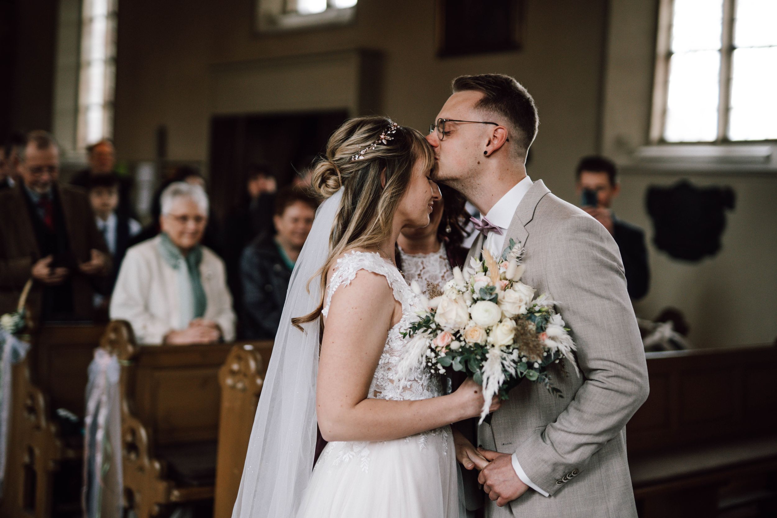 Bride and groom sharing emotional first look moment in church setting.