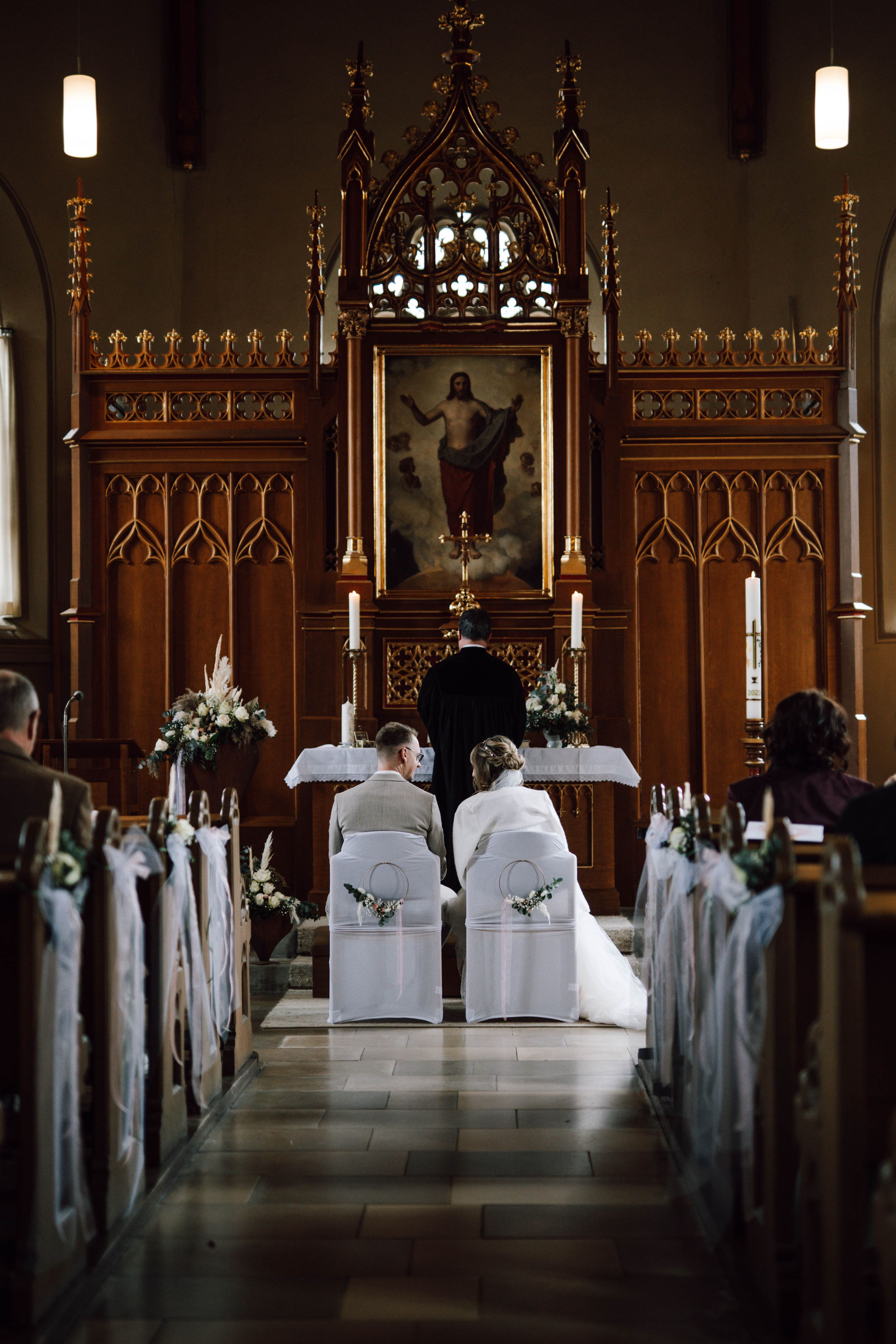 Gothic church interior decorated for wedding ceremony with white flowers and wooden details.