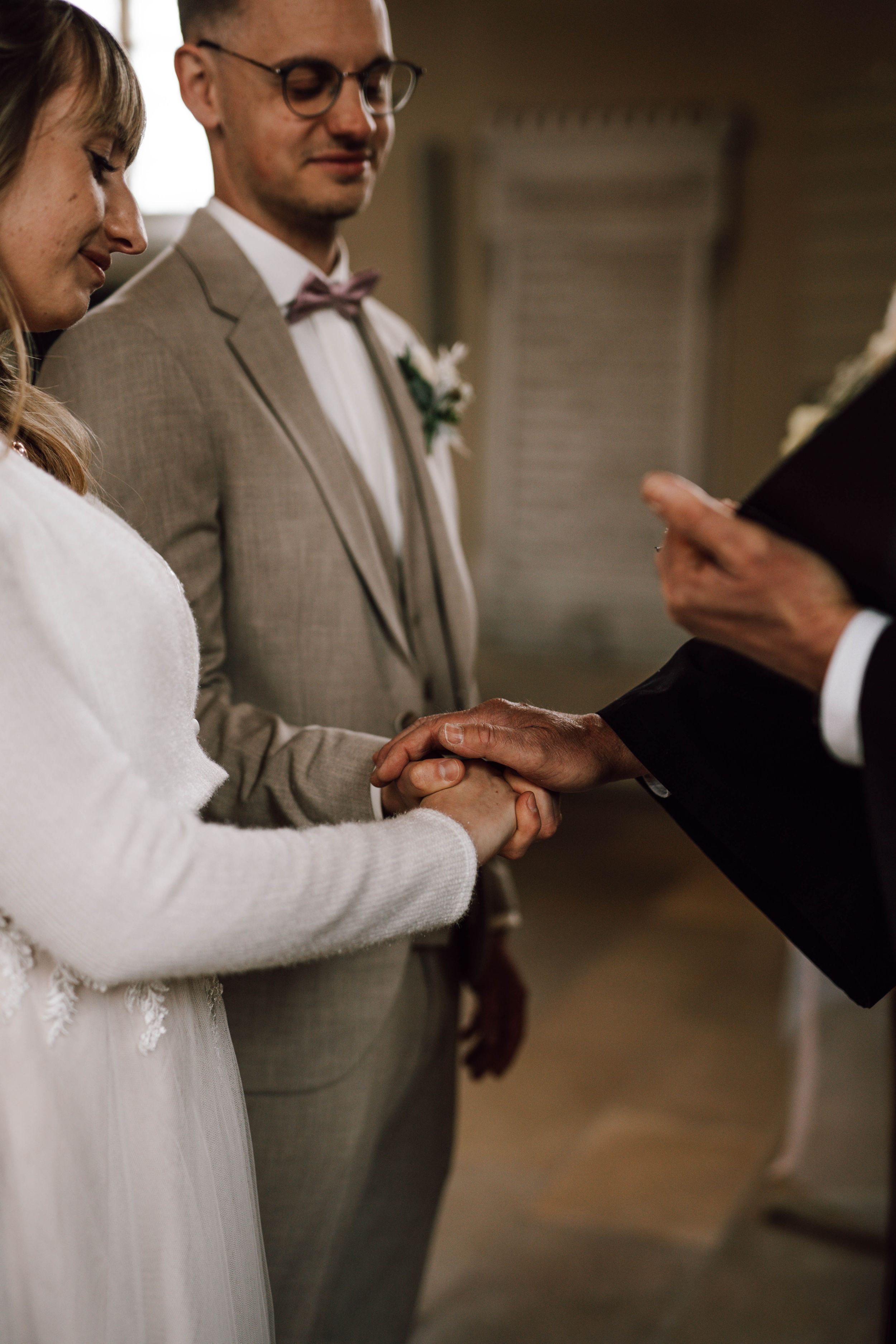 Wedding ceremony moment showing hands during ring exchange with officiant.
