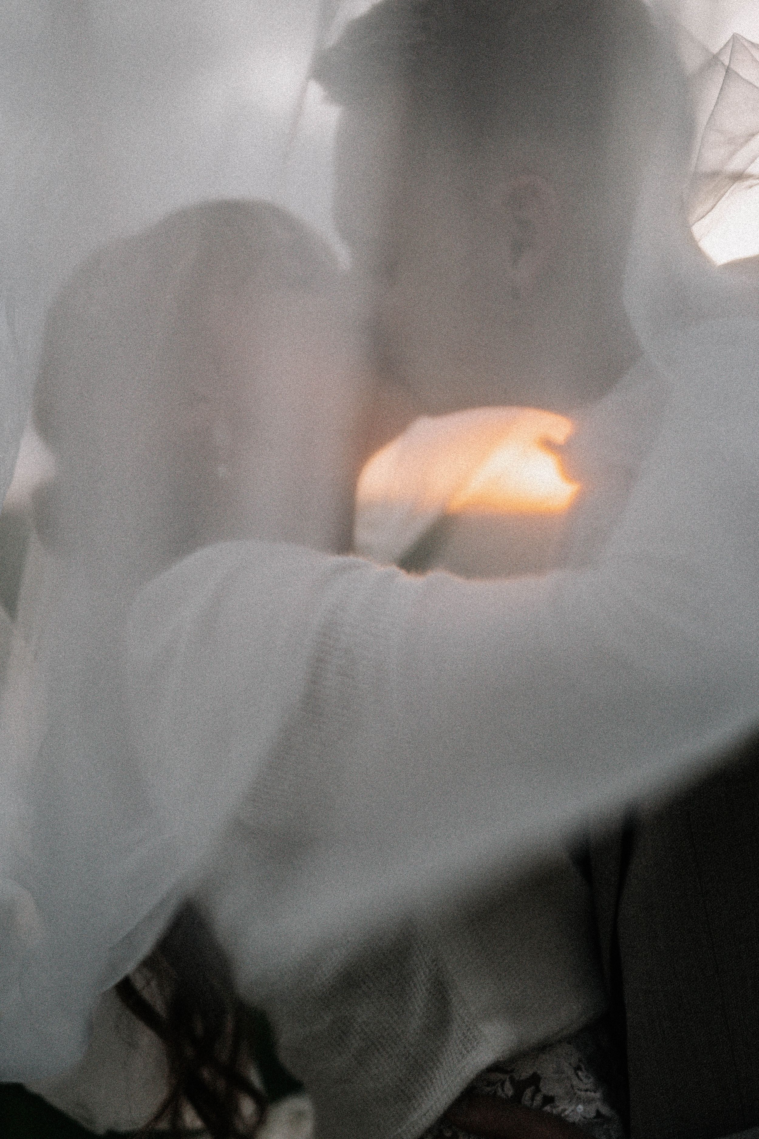 Artistic silhouette of wedding couple with sunset glow through veil.