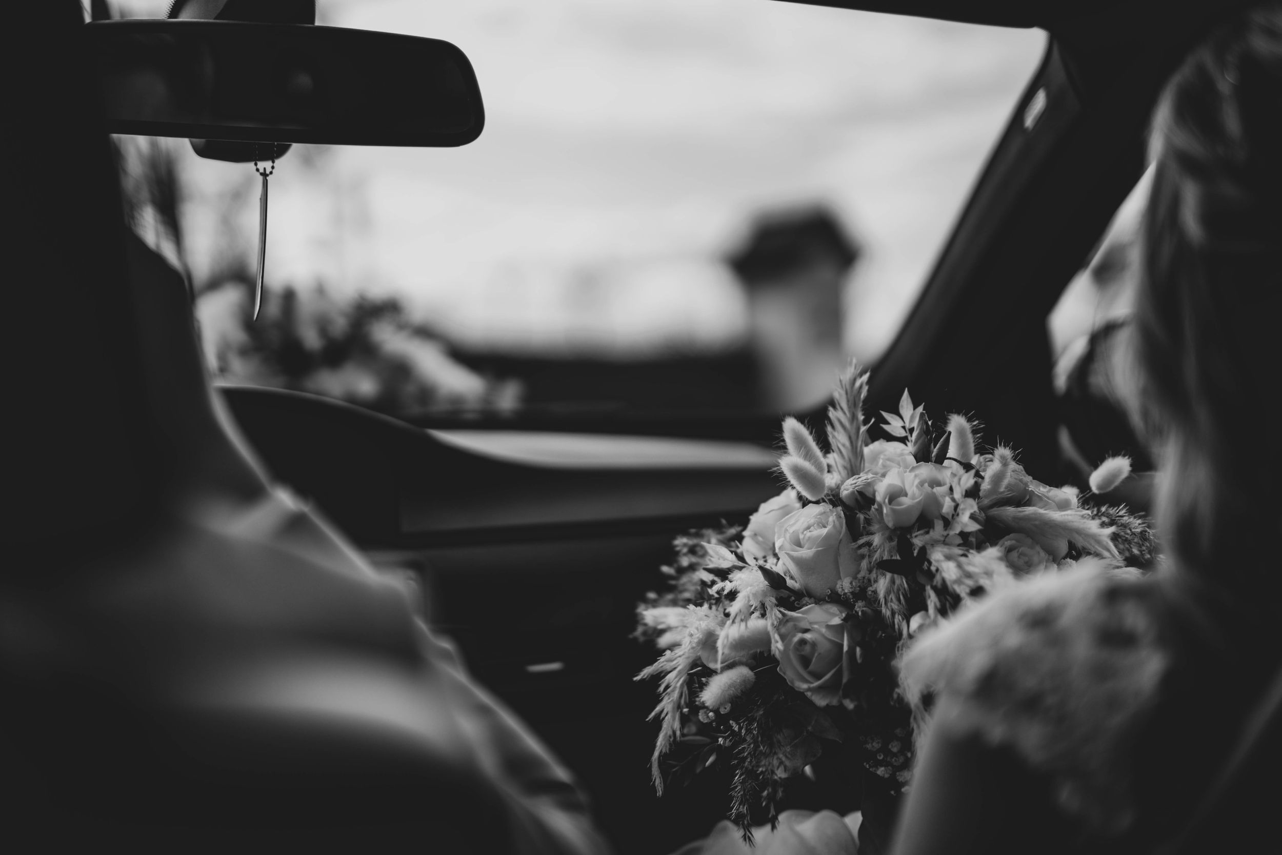 Black and white photo of wedding flowers in car interior.