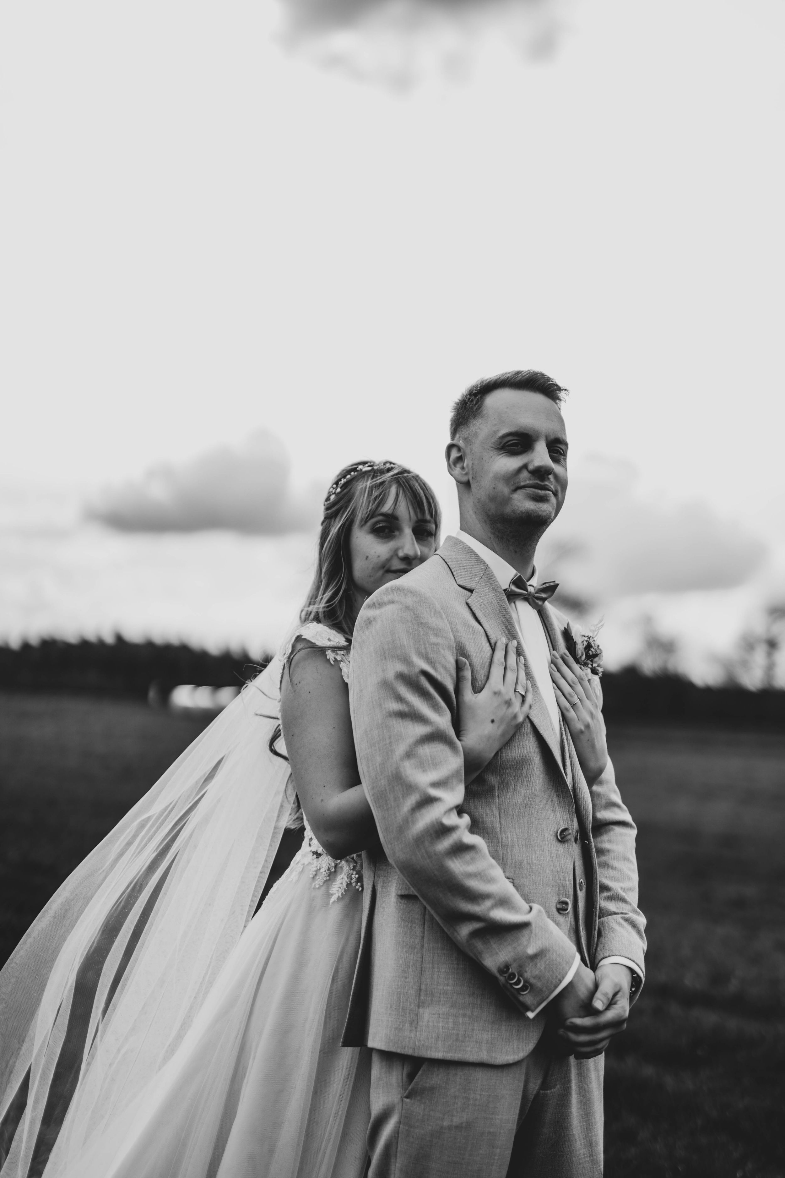 Black and white portrait of newlyweds standing in an outdoor setting.