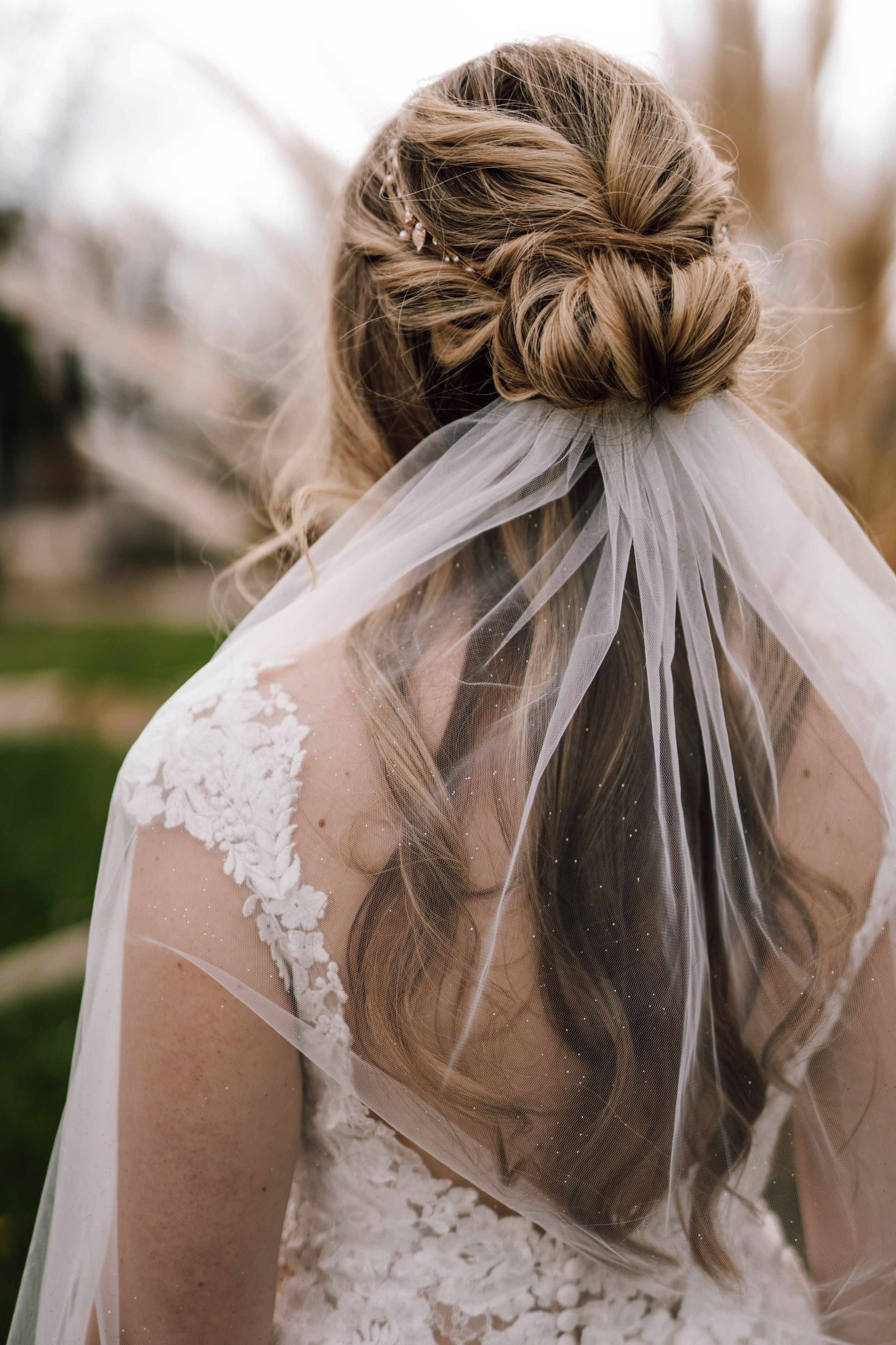 Elegant bridal hairstyle with twisted bun and flowing veil detail.