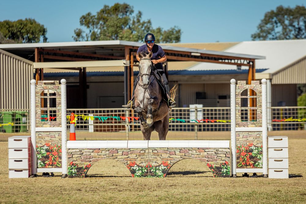 Horse and rider clearing a decorated show jumping fence with precision.