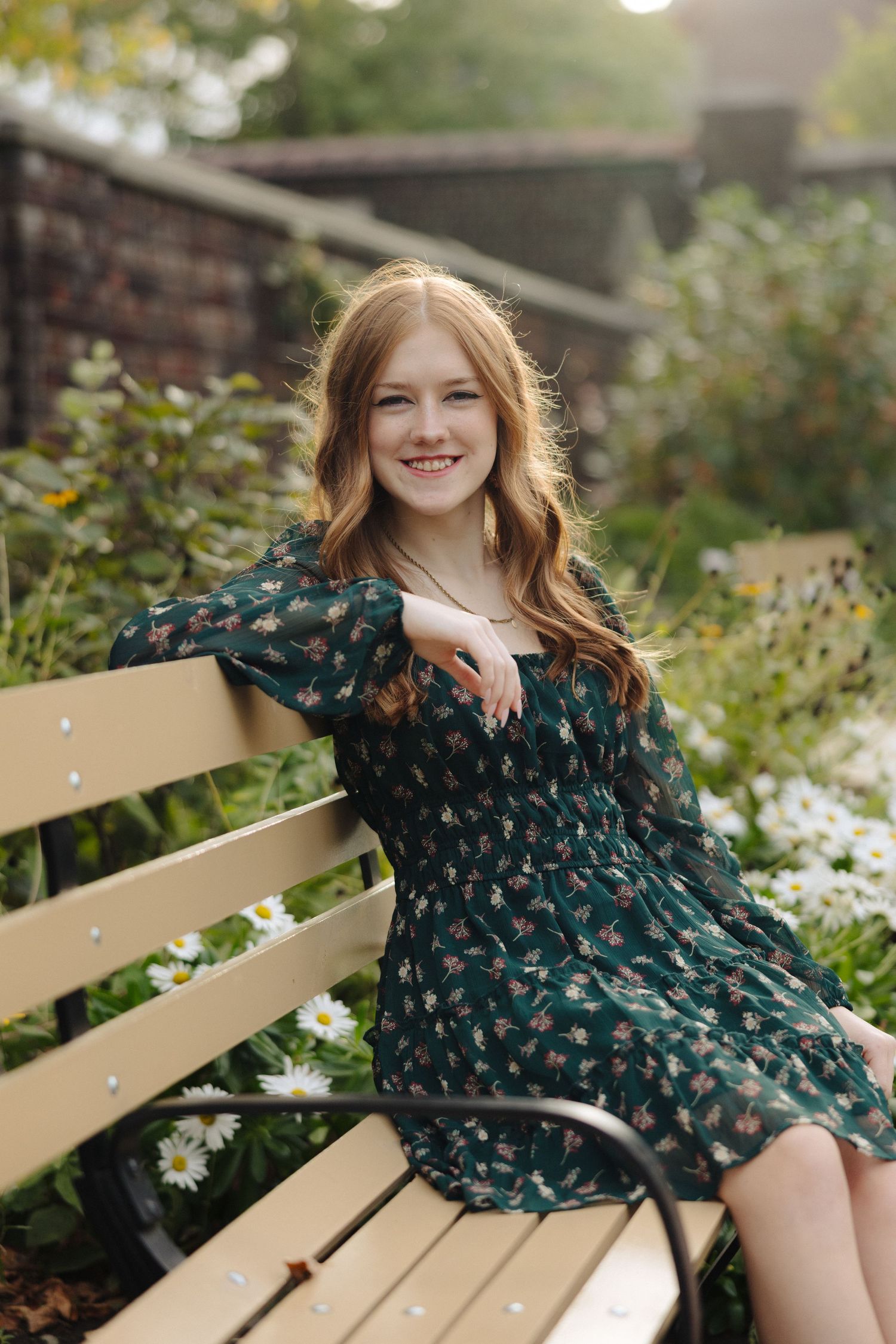 A woman in a floral dress relaxes on a wooden bench surrounded by garden flowers.