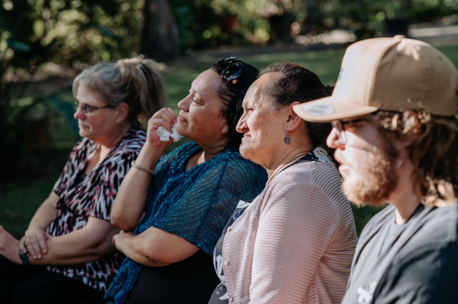 Wedding guests sharing a laugh while seated during an outdoor ceremony.