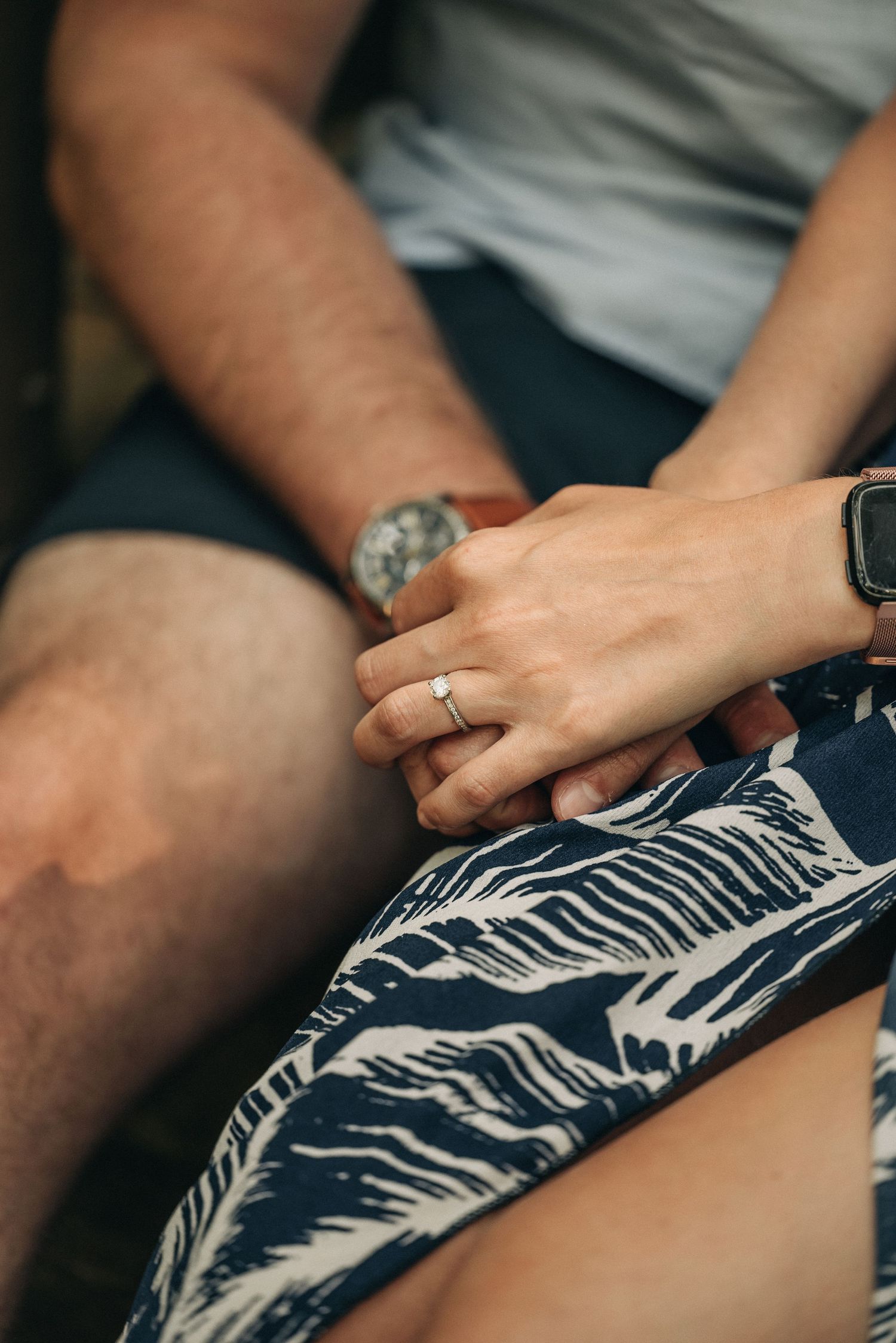 Close-up shot of hands with an engagement ring against a blue floral dress.