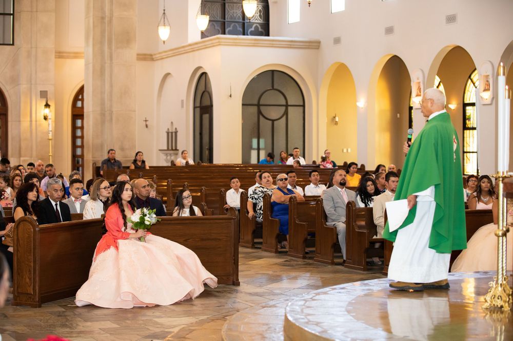 Wedding ceremony in a traditional church with priest in green robes and bride in pink dress.