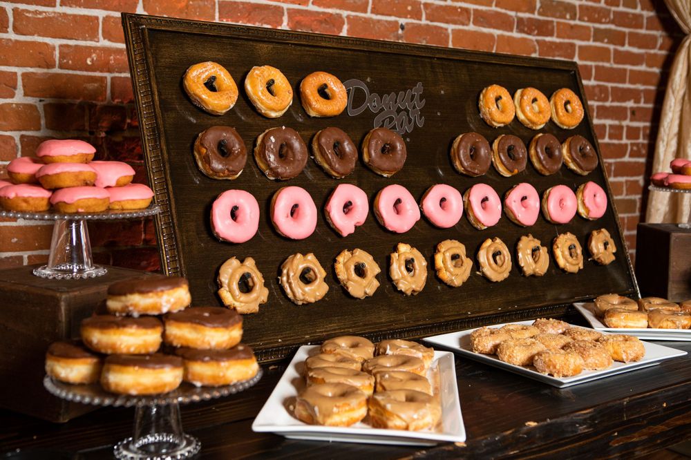 Colorful donuts displayed on a black wall mount with pink, chocolate, and glazed varieties.